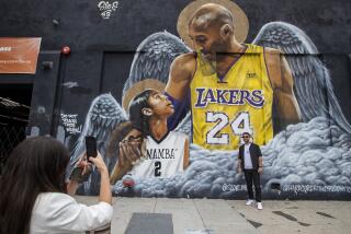 Maria Eastaldo photographs her husband Salvatore Pesante in front of a mural of Lakers legend Kobe Bryant and daughter Gianna