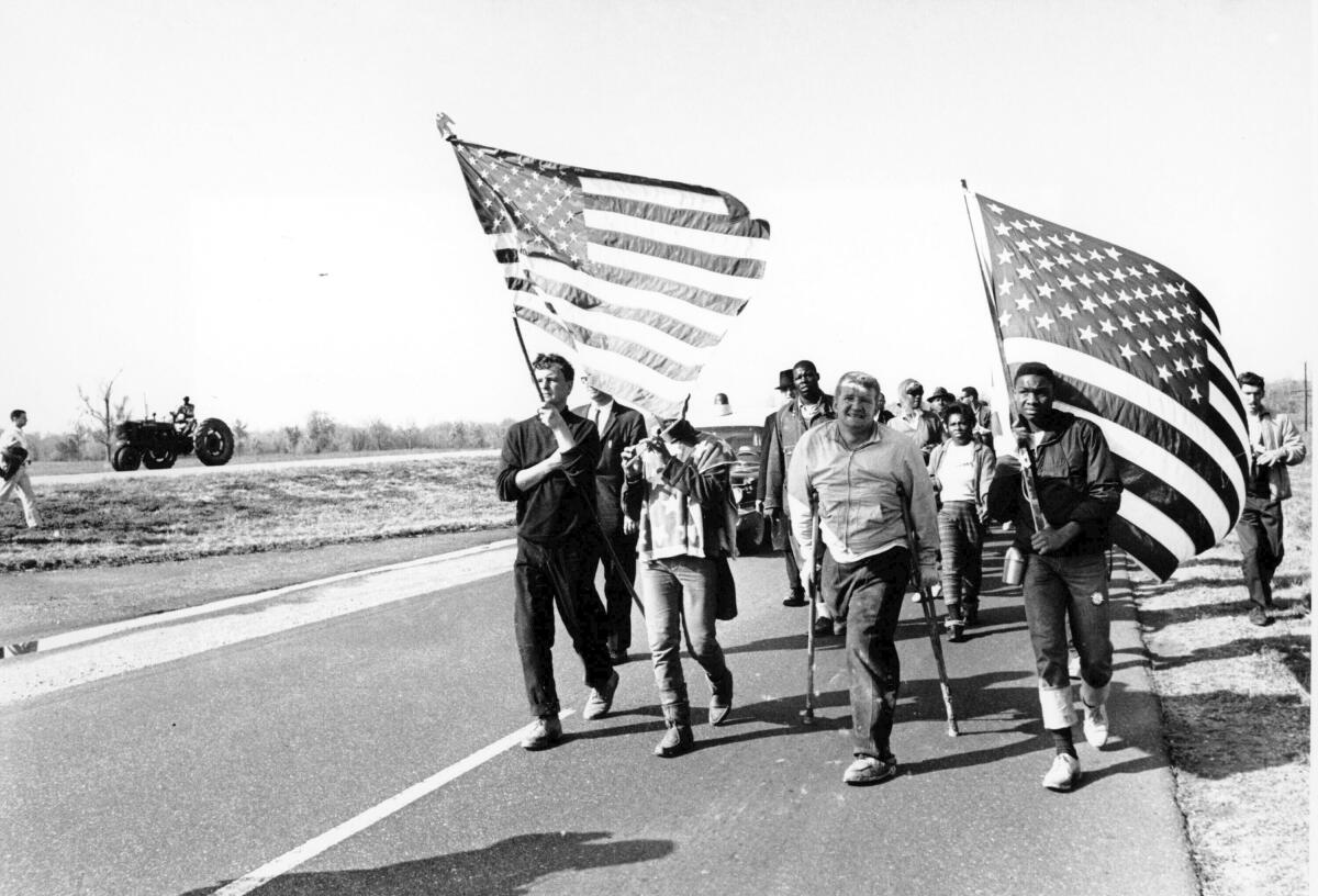 Civil rights marchers in black-and-white photo carrying American flags