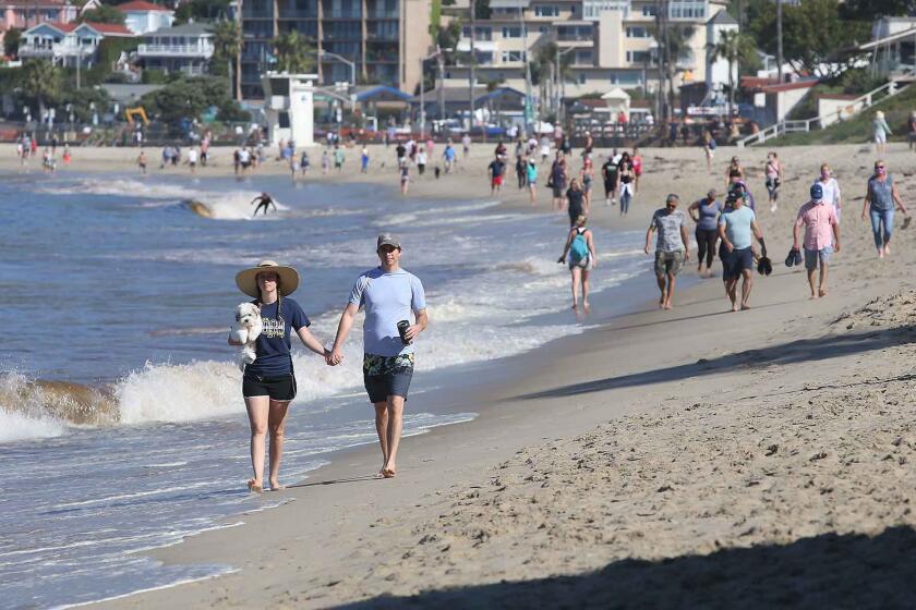 Beach-goers walk the sands between Cleo St. and Main as Laguna opened their beaches for recreation use between the hours of 6 to 10am on Tuesday. The beach will open for use Monday through Friday.