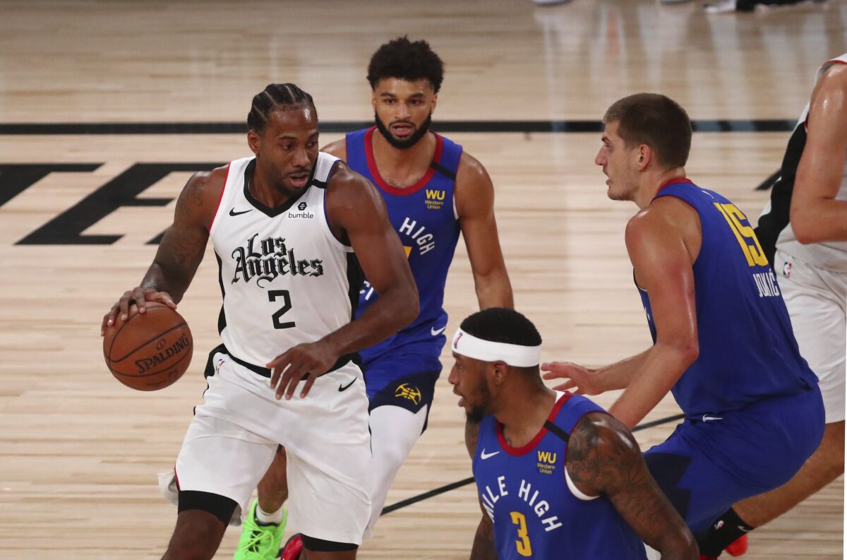 Clippers star Kawhi Leonard faces the double-team defense of Nuggets center Nikola Jokic and guard Jamal Murray on Aug. 12.