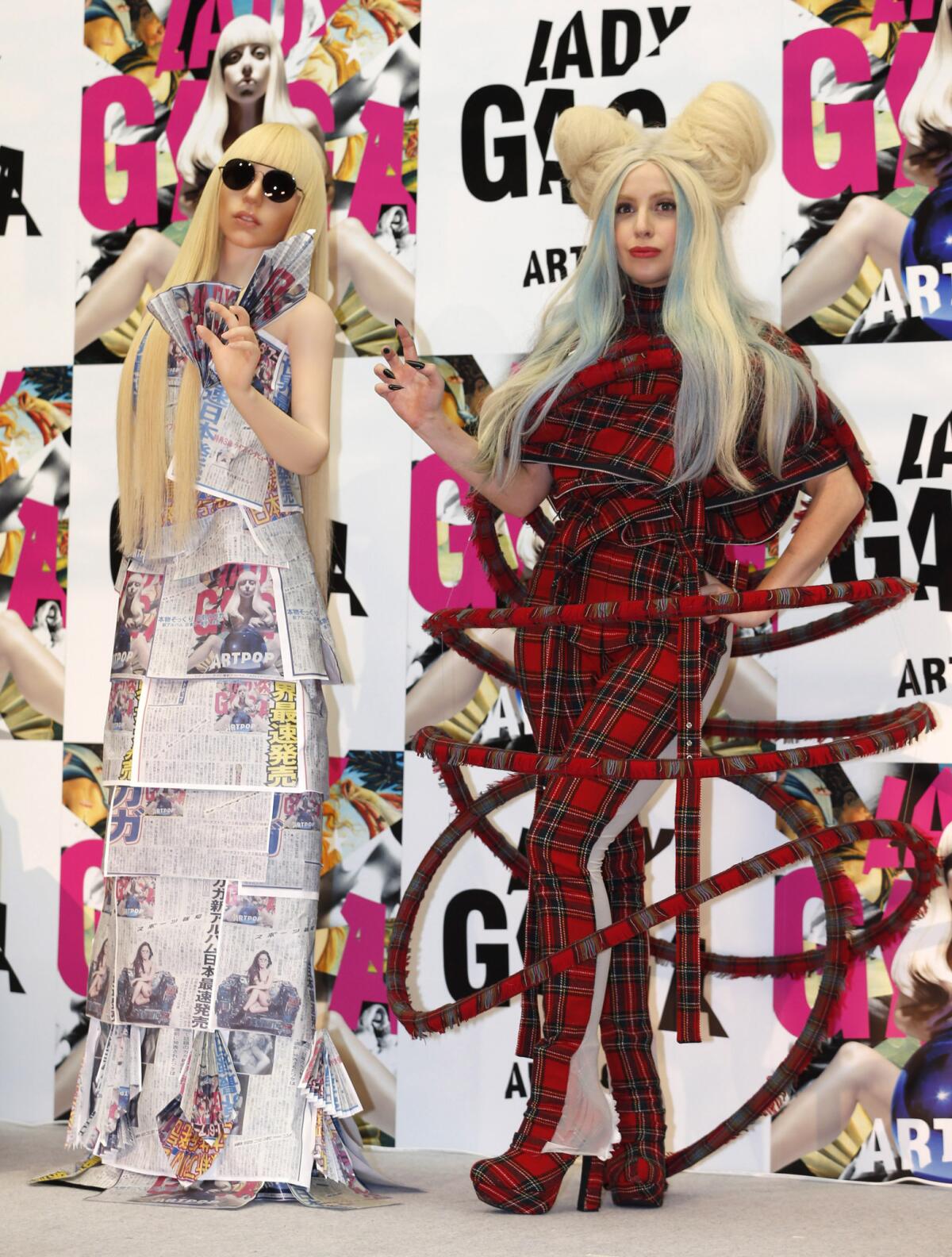 Lady Gaga, in plaid, poses with a life-sized Lady Gaga doll at a news conference in Tokyo to promote her album "ArtPop."