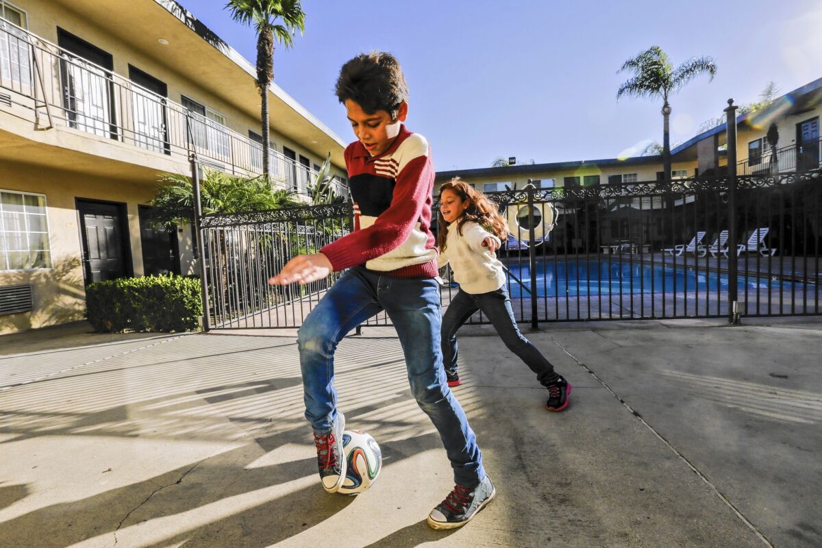 Syrian refugees Omran and Maram Wawieh, 11 and 8, play in the courtyard of the Pomona motel where their family is staying.