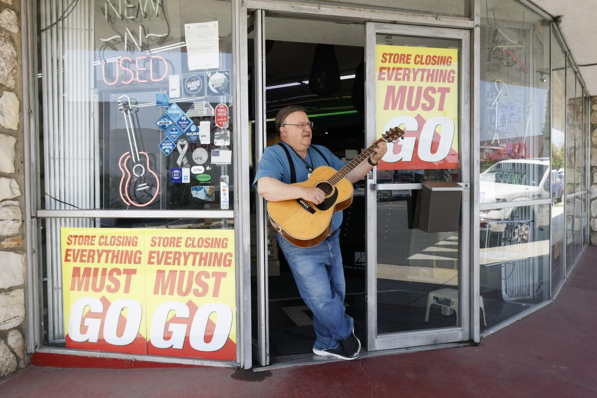Ed Intagliata stands outside his store holding the first guitar he ever sold.