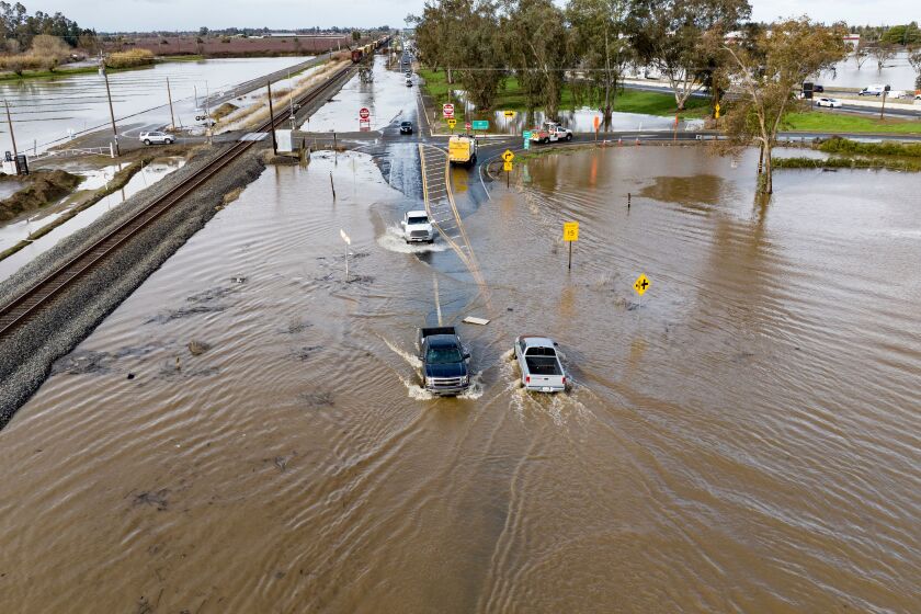 This aerial view shows vehicles driving on a flooded road in Merced, California on January 10, 2023. - A massive storm called a bomb cyclone" by meteorologists has arrived and is expected to cause widespread flooding throughout the state. (Photo by JOSH EDELSON / AFP) (Photo by JOSH EDELSON/AFP via Getty Images)