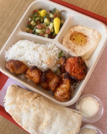 The chicken kebab plate from Zankou Chicken comes with rice, garlic sauce and a roasted tomato.