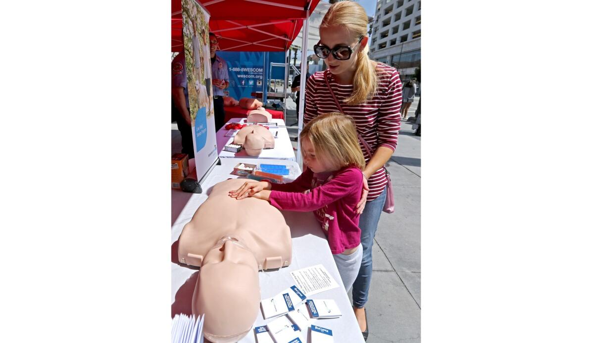 Glendale resident Lila Boone, 5, with her mother Shay Boone, learns hands-only CPR during Sidewalk CPR Day in front of the Glendale Galleria on Thursday, June 6, 2019.