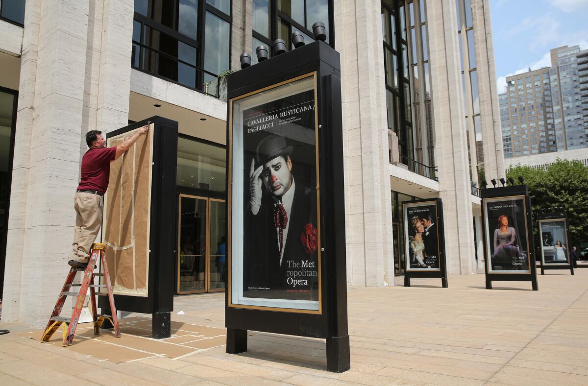 A worker unveils an advertisement for future productions at the Metropolitan Opera at Lincoln Center in New York. The ongoing labor dispute may jeopardize the upcoming Met season.