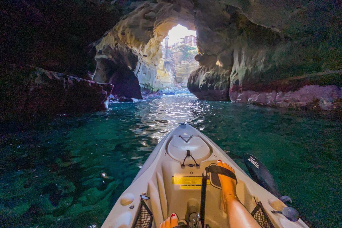 The prow of a kayak pointed toward a sea cave opening