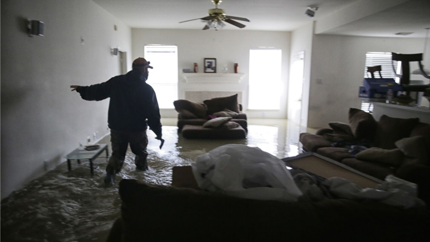 Jan Tullos, 32, searches a flooded home for an injured woman who was reportedly stranded inside in Clodine, Texas. The home was empty.