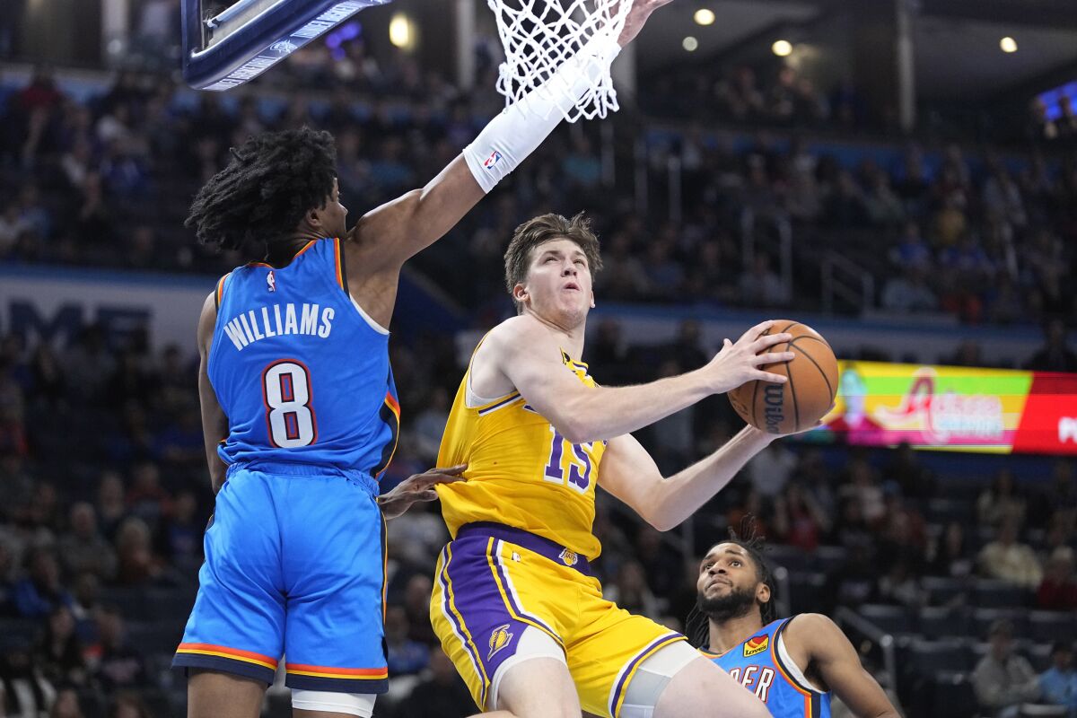 Lakers guard Austin Reaves goes to the basket between Oklahoma City Thunder forward Jalen Williams and guard Isaiah Joe.