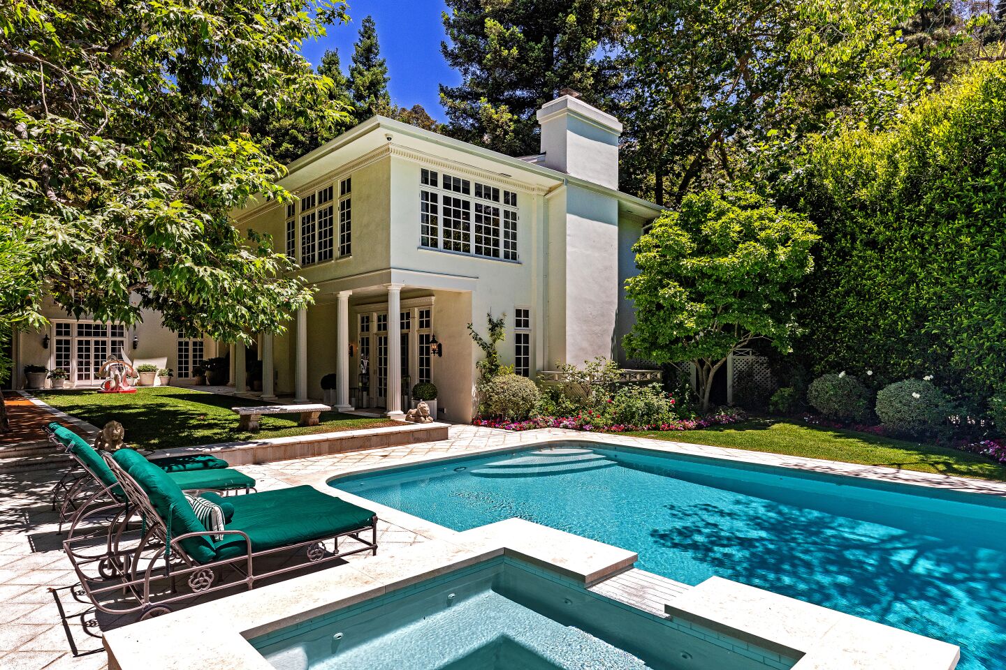 A rectangular pool and hot tub with deck chairs outside a white traditional-style home in Bel-Air