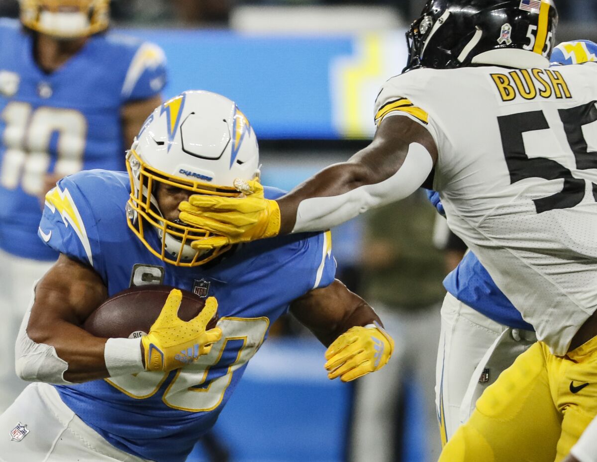 Steelers linebacker Devin Bush, right, whacks Chargers running back Austin Ekeler in the face in the first half.