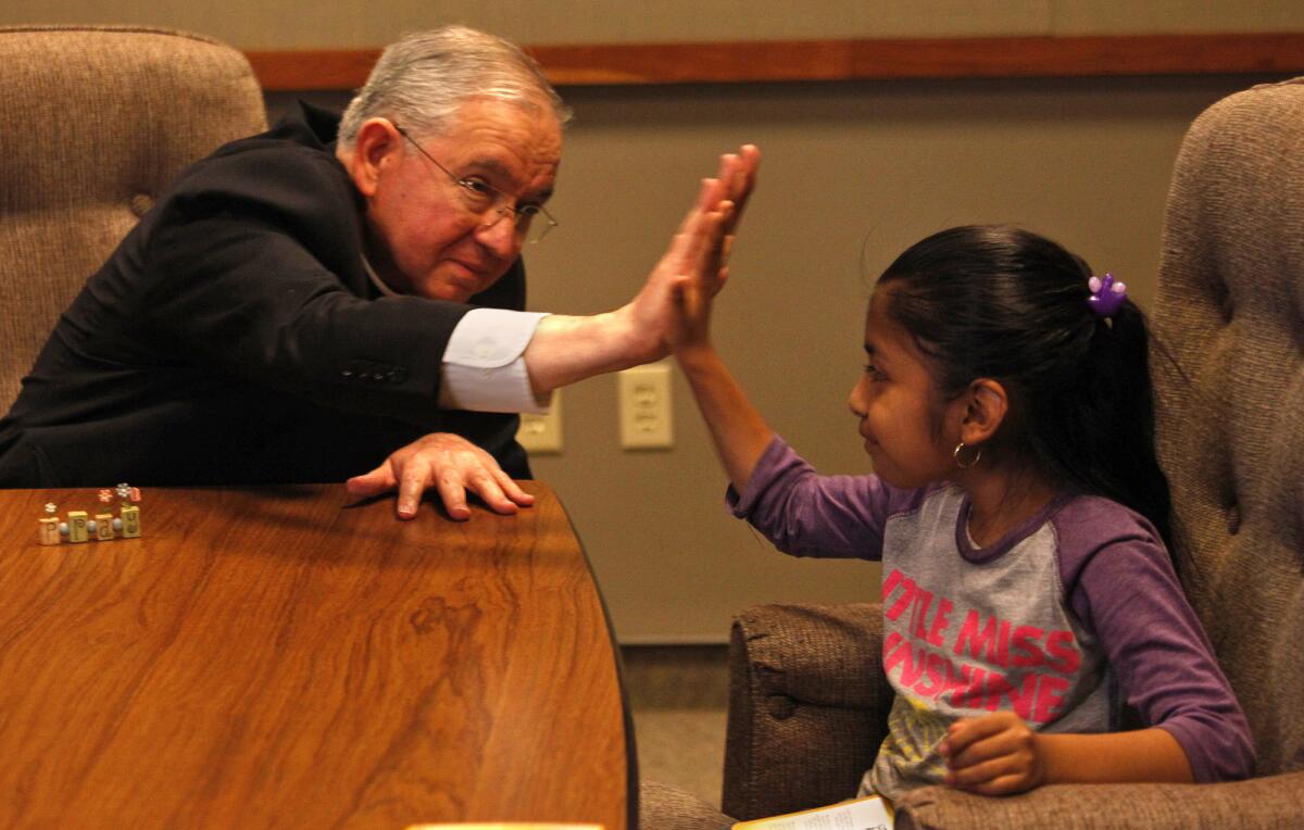 Los Angeles Archbishop José Gomez gives Jersey Vargas, 10, a high-five in support of her trip to the Vatican in 2014, where she hoped to get an audience with Pope Francis to try to prevent her father from being deported to Mexico.
