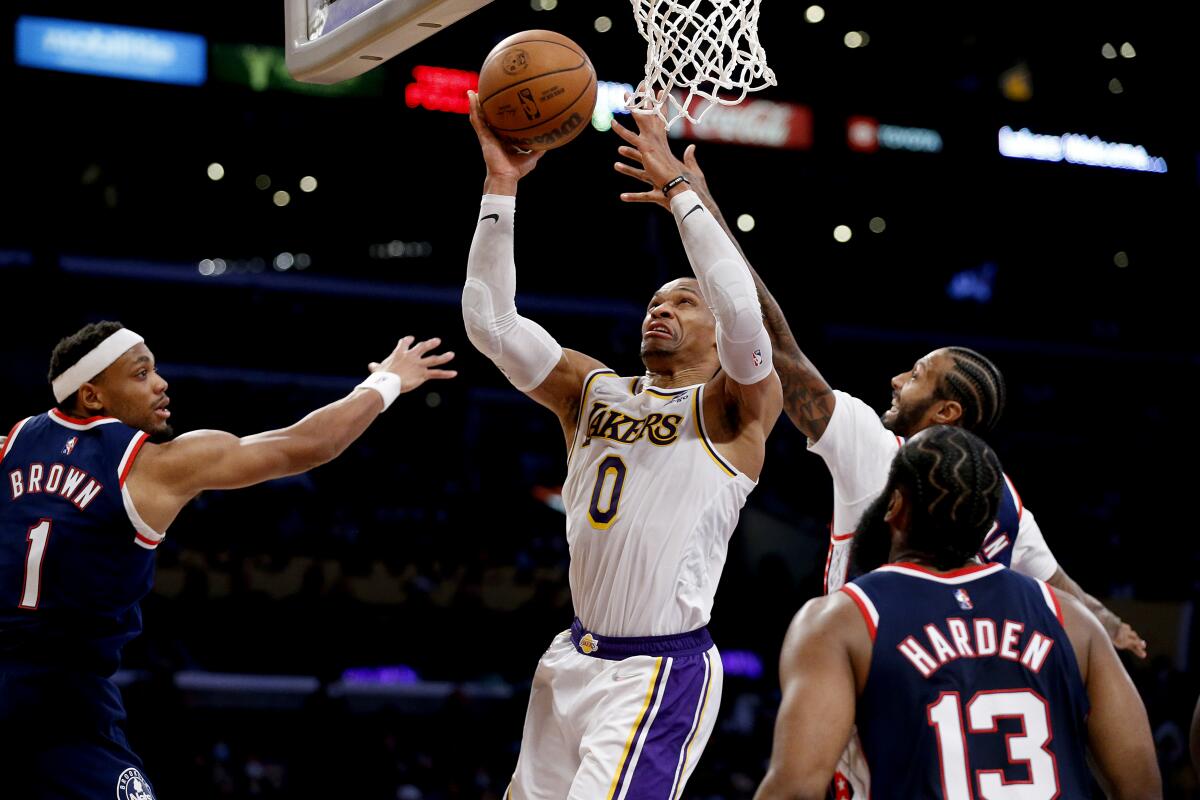 Lakers guard Russell Westbrook scores a basket guarded by Brooklyn Nets forwards Bruce Brown and James Johnson.