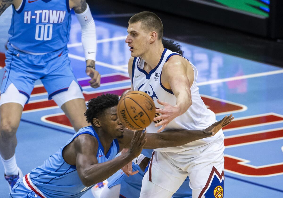 Denver Nuggets center Nikola Jokic (15) passes to a teammate while being defended by Houston Rockets forward Jae'Sean Tate (8) and guard Kevin Porter Jr. (3) during the third quarter of an NBA basketball game Friday, April 16, 2021, in Houston. (Mark Mulligan/Houston Chronicle via AP)
