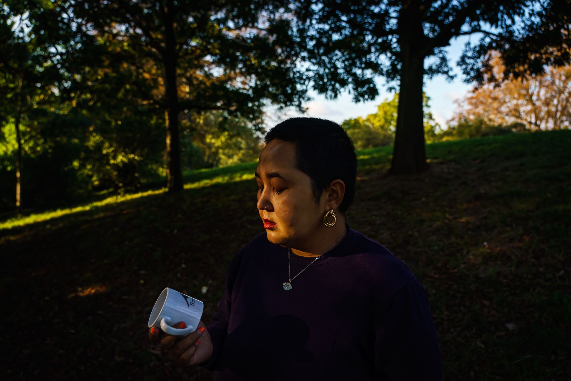 A woman looks at a white coffee cup.