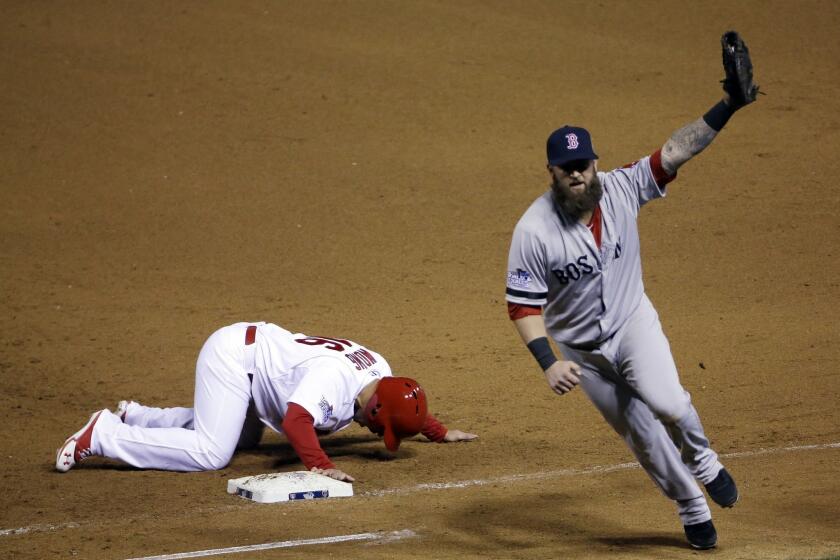 Boston Red Sox first baseman Mike Napoli, right, celebrates after tagging out St. Louis Cardinals pinch-runner Kolten Wong on a pick-off throw to end Game 4 of the World Series on Sunday.