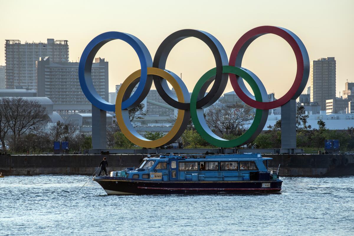 A man pulls up the anchor on a pleasure boat moored next to the Tokyo 2020 Olympic Rings.