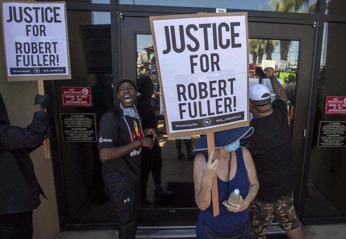 Demonstrators outside a sheriff's station hold signs demanding an investigation into the death of Robert Fuller
