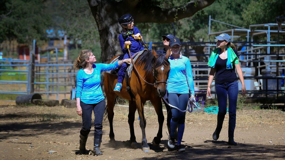 Surrounded by volunteers, Kimberly Penick goes on a horseback ride that takes her around the horse arena and stables in east Poway at the Ride Above Disability Therapeutic Riding Center. Left-right, Sharon Mann, Kimberly Penick, Danica Taylor, Natalie Parker and Riley Burkart.