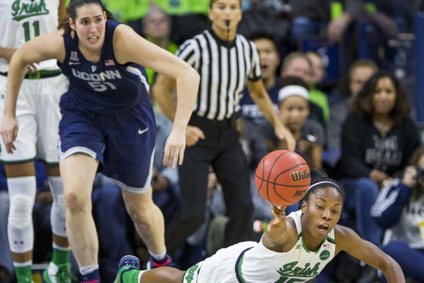 Notre Dame's Lindsay Allen (15) dives for a loose ball in front of Connecticut's Natalie Butler (51) during the first half of a game on Wednesday.