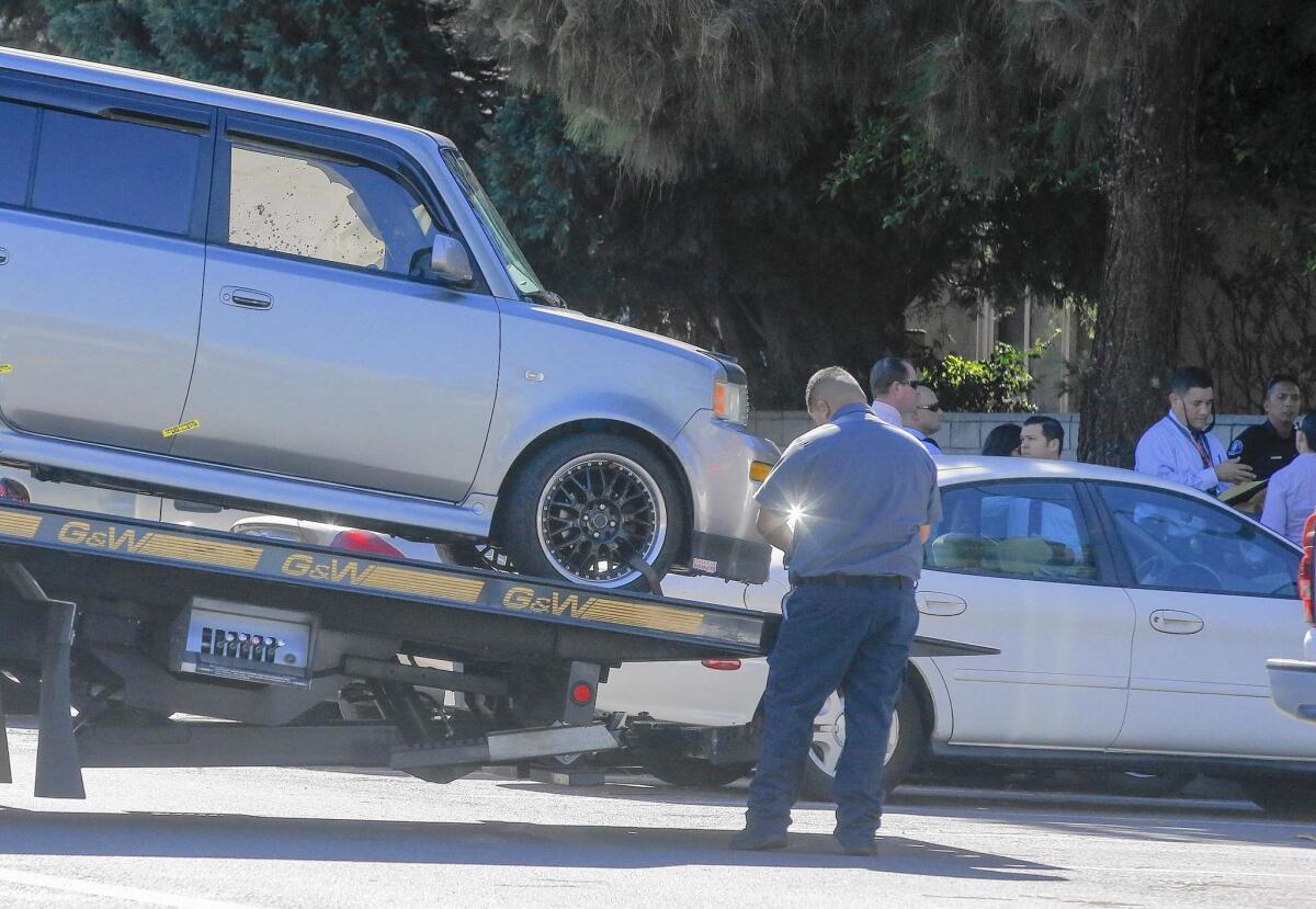 A tow truck operator removes a blood-stained vehicle after a man was found dead in the 2300 block of Vanguard Way in Costa Mesa on Wednesday. A nearby resident said she saw a man swinging a tool into a car from outside of it and then saw the man removing what looked like “a bloody body” from the car.