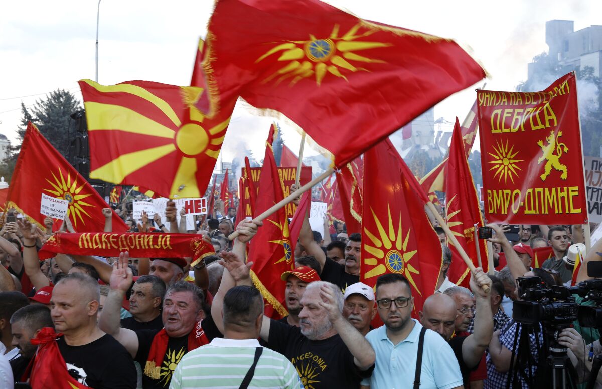 People wave the old and the current national flags as they attend a protest in front of the government building in Skopje, North Macedonia, on Saturday, July 2, 2022. Tens of thousands of people gathered late Saturday outside government offices in North Macedonia’s capital to protest the latest proposal on solving a dispute with Bulgaria in order for North Macedonia to open membership talks with the European Union. (AP Photo/Boris Grdanoski)