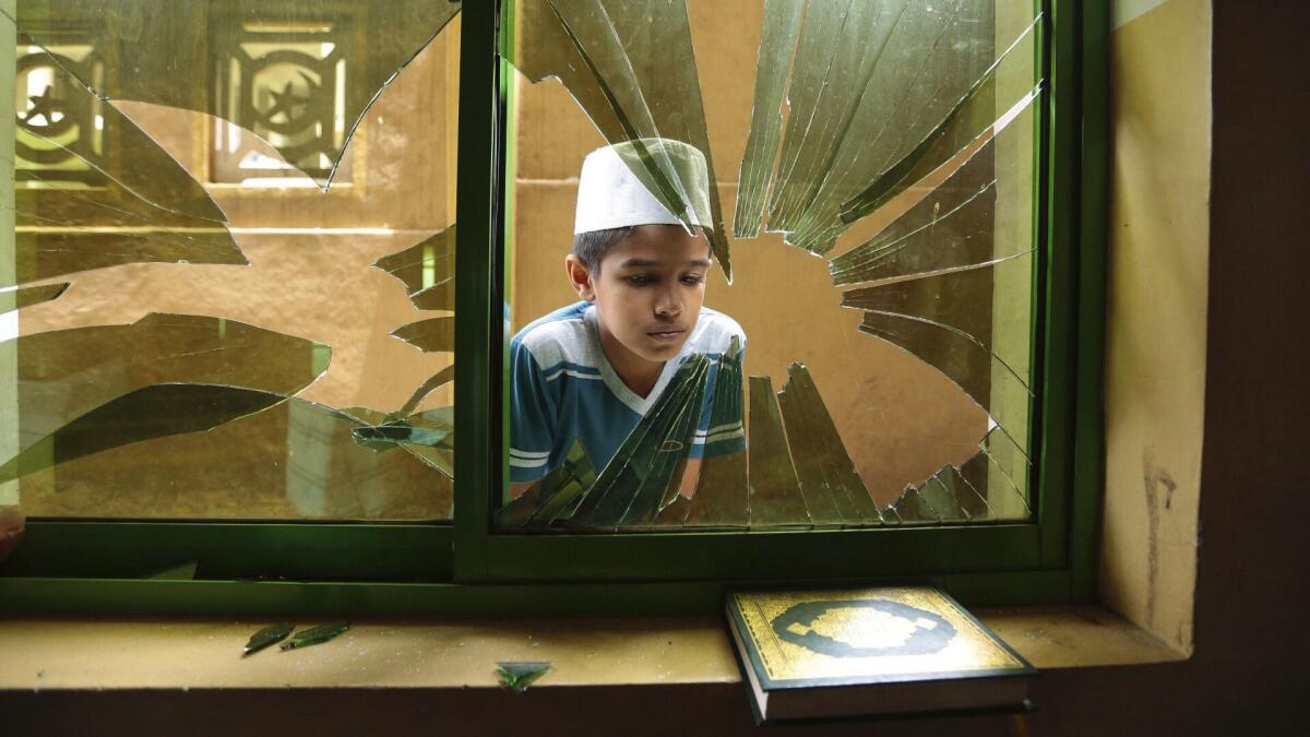 A Muslim boy peeps through a broken window of a vandalized mosque in Kandy, Sri Lanka, on March 9, 2018.
