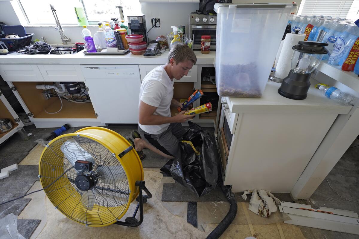 Jordan Cromer cleans water-logged items at his home, Tuesday, Oct. 4, 2022, in North Port, Fla. 
