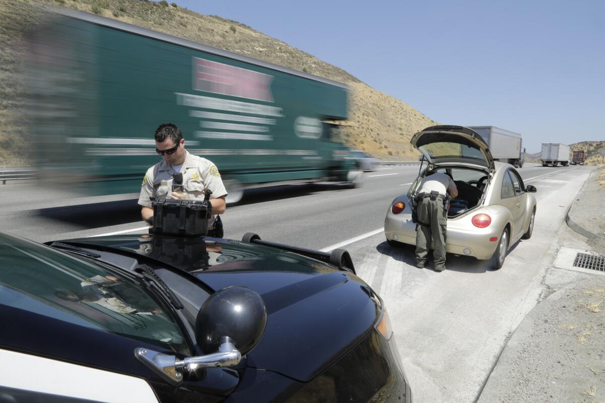Los agentes Michael Vann, a la izquierda, y John Leitelt revisan el vehículo del hombre. (Myung J. Chun / Los Angeles Times)