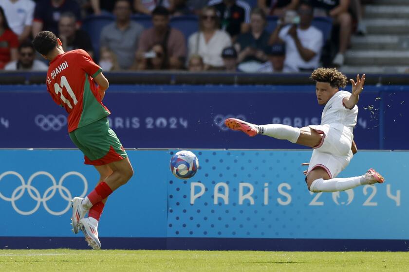 Kevin Paredes of the United States takes a shot as Morocco's Zakaria El Ouahdi closes in.