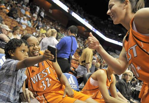 Dyllan Thompson Jones, 4, son of Western Conference All-Star Tina Thompson (middle), shows Sue Bird, Thompson's All-Star teammate, a picture he took of Bird before the WNBA All-Star game Saturday at Mohegan Sun Arena in Uncasville. Bird is a former UConn point guard.