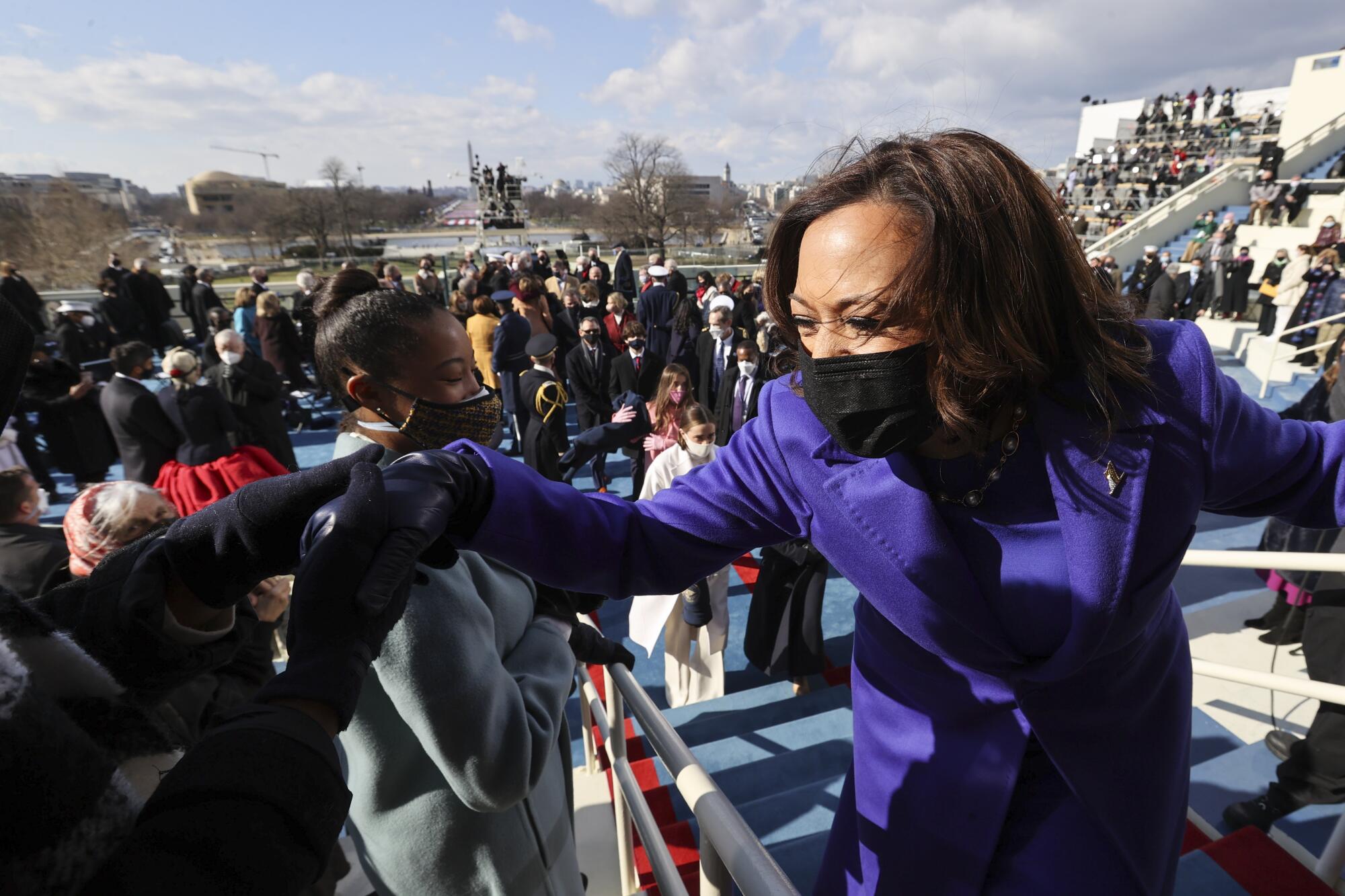 Vice President Kamala Harris shakes hands while rising from her seat after she was inaugurated. People are in the background