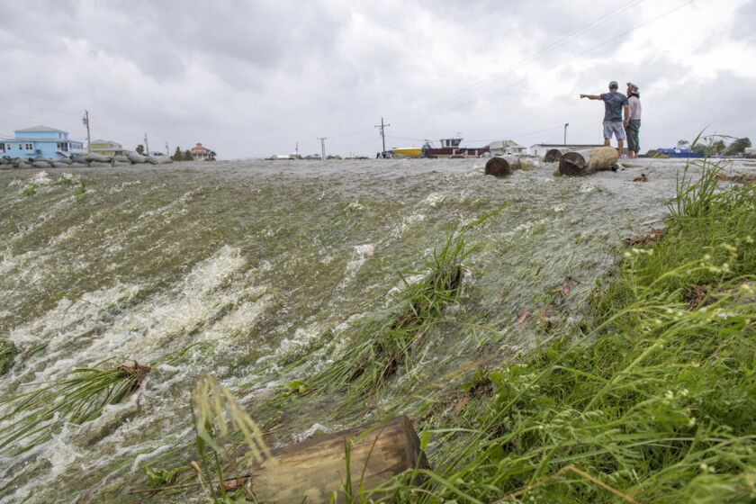 Dos personas miran el agua de mar que superó un dique en el distrito de Plaquemines, al sur de Nueva Orleans, mientras el huracán Barry tocaba tierra en la costa.