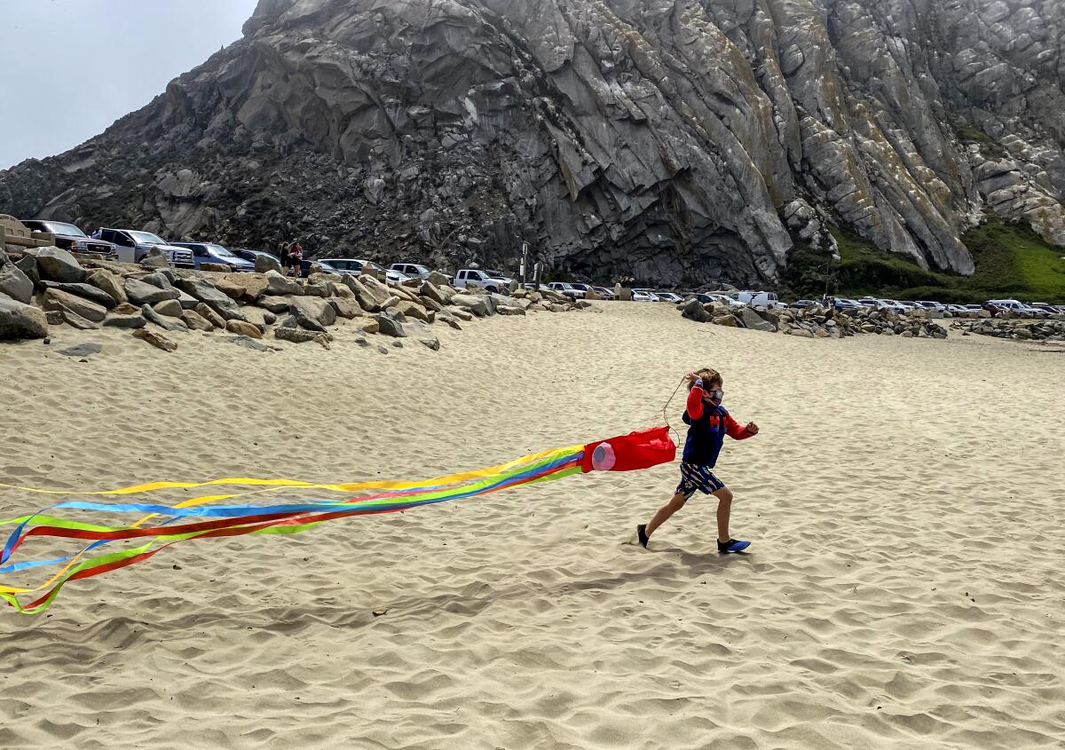 A young visitor attempts to launch a kite on Morro Rock Beach.