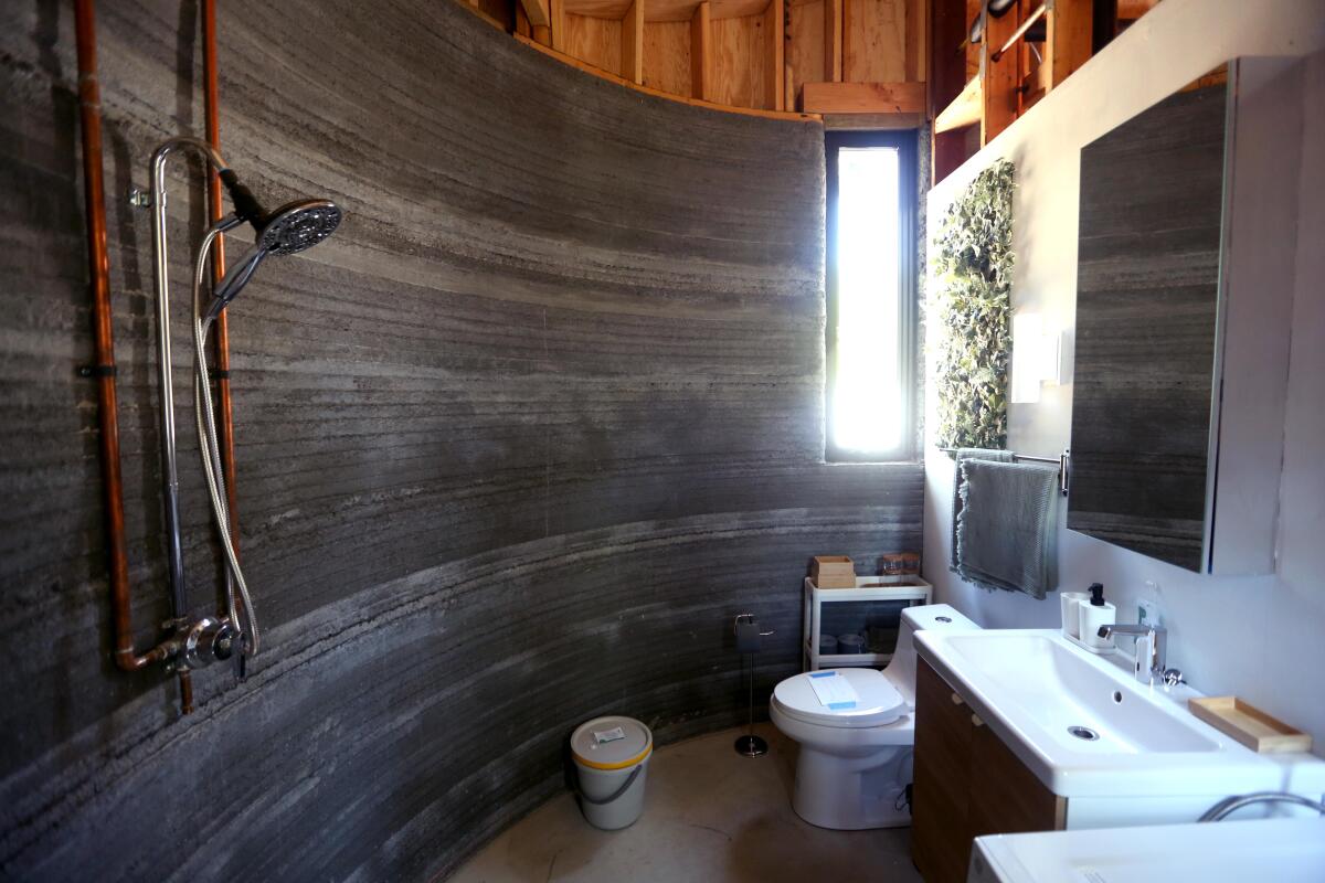 A view of a bathroom area with a gently curved wall made of narrow horizontal ridges of concrete