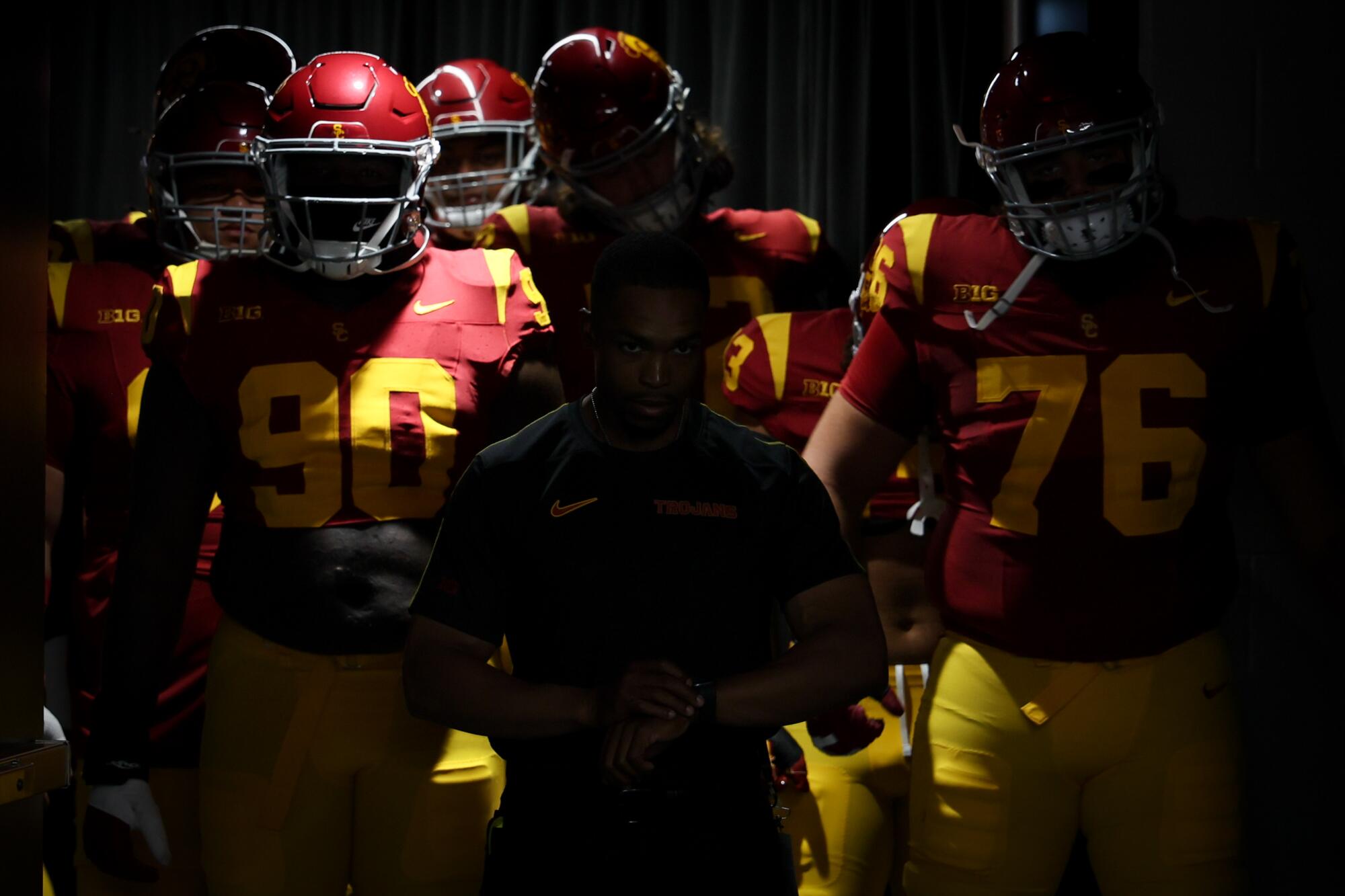 USC football players make their way through darkness and scattered rays of light onto the field before the game 