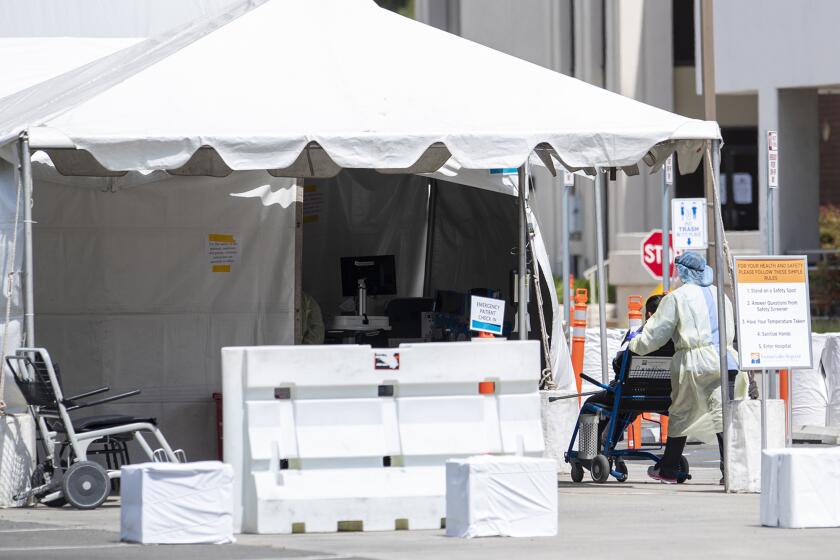 A medical professional wheels a patient into a tent outside the emergency room of the Fountain Valley Regional Hospital & Medical Center on Thursday, April 2.