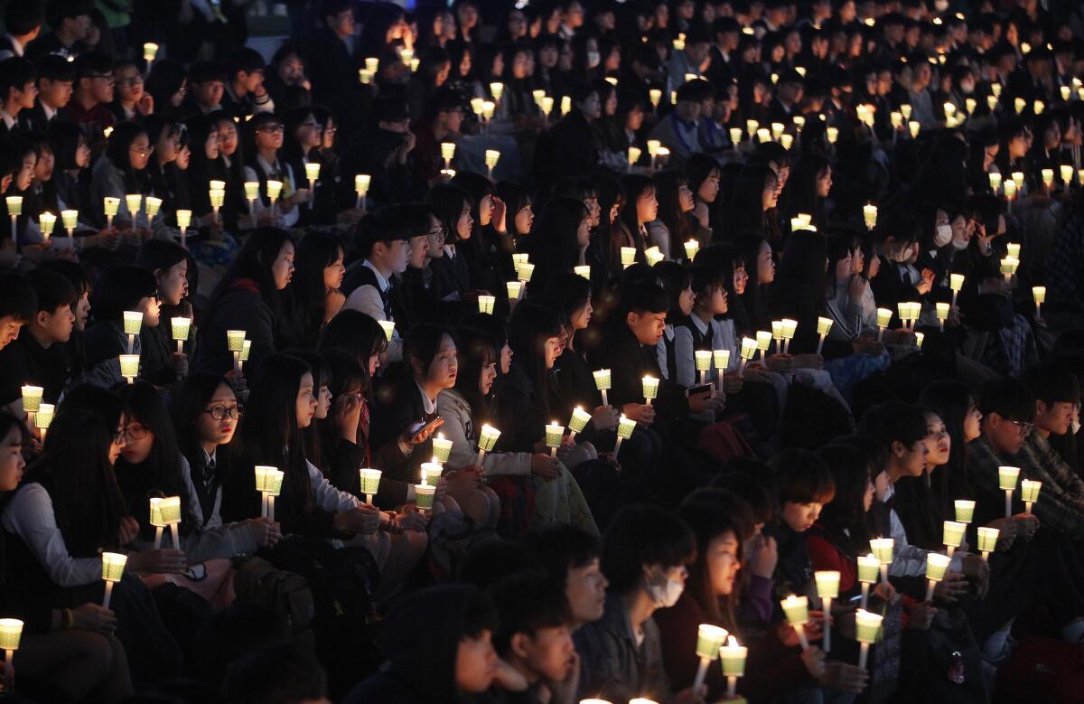 High school students hold candles to pay their respects to the victims of the Sewol ferry disaster during a ceremony April 15 on the eve of the sinking's two-year anniversary in Ansan, South Korea