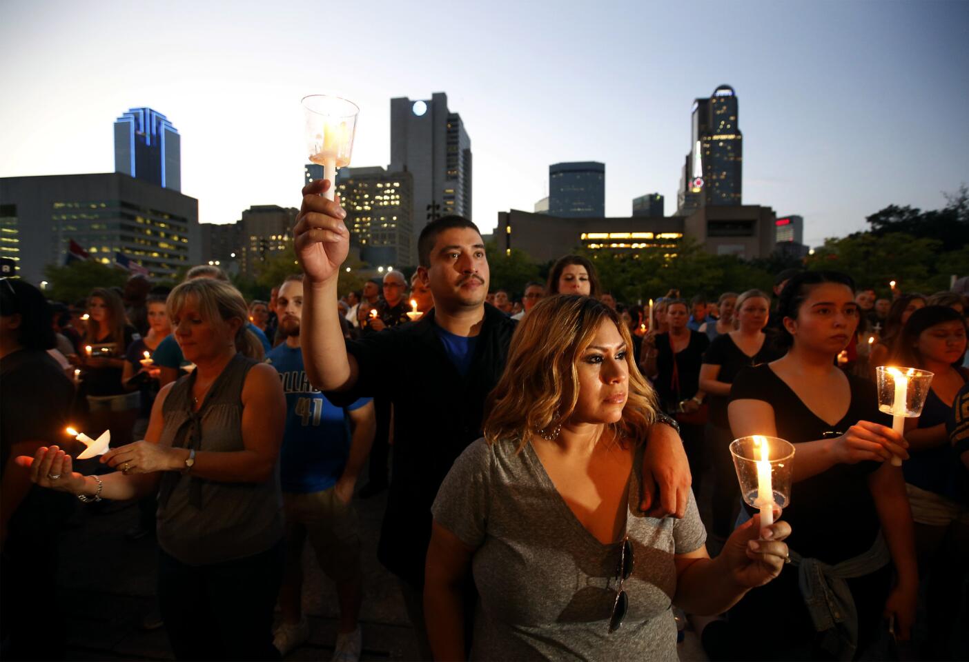 Dallas Police Officer Victor Guzman, who was on the sniper shooting scene, holds a candle with his wife Ciprina as family and friends of fallen police officers take part in a candlelight vigil at City Hall in Dallas.