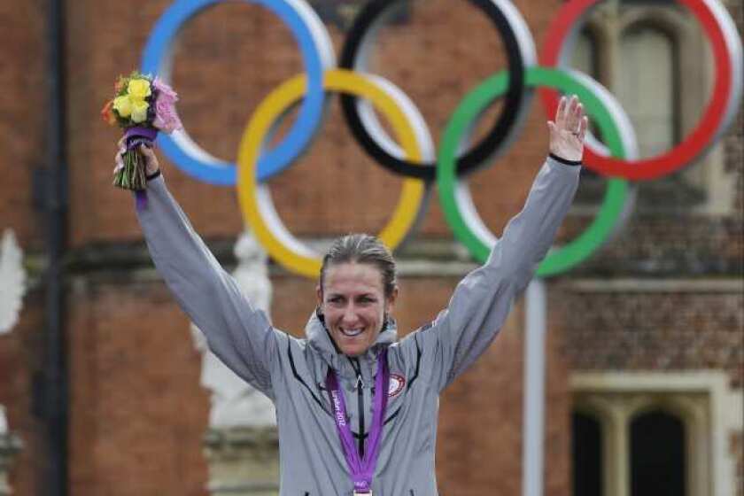 Road cyclist Kristin Armstrong, a former triathlete, triumphantly displays her gold medal in women's individual time trial.