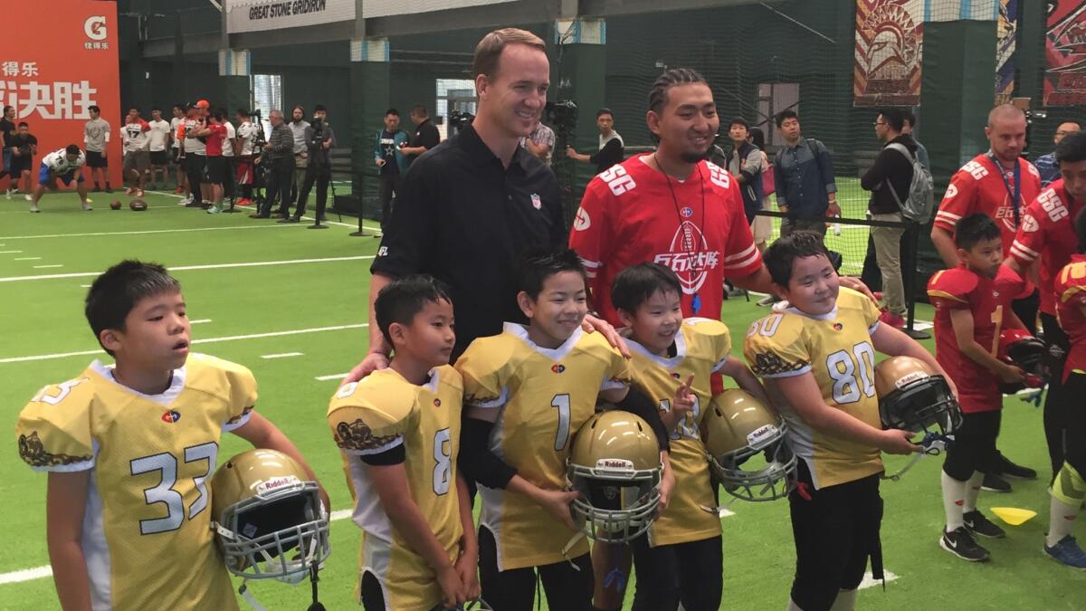 Participants in a football clinic take a photo with retired NFL quarterback Peyton Manning.