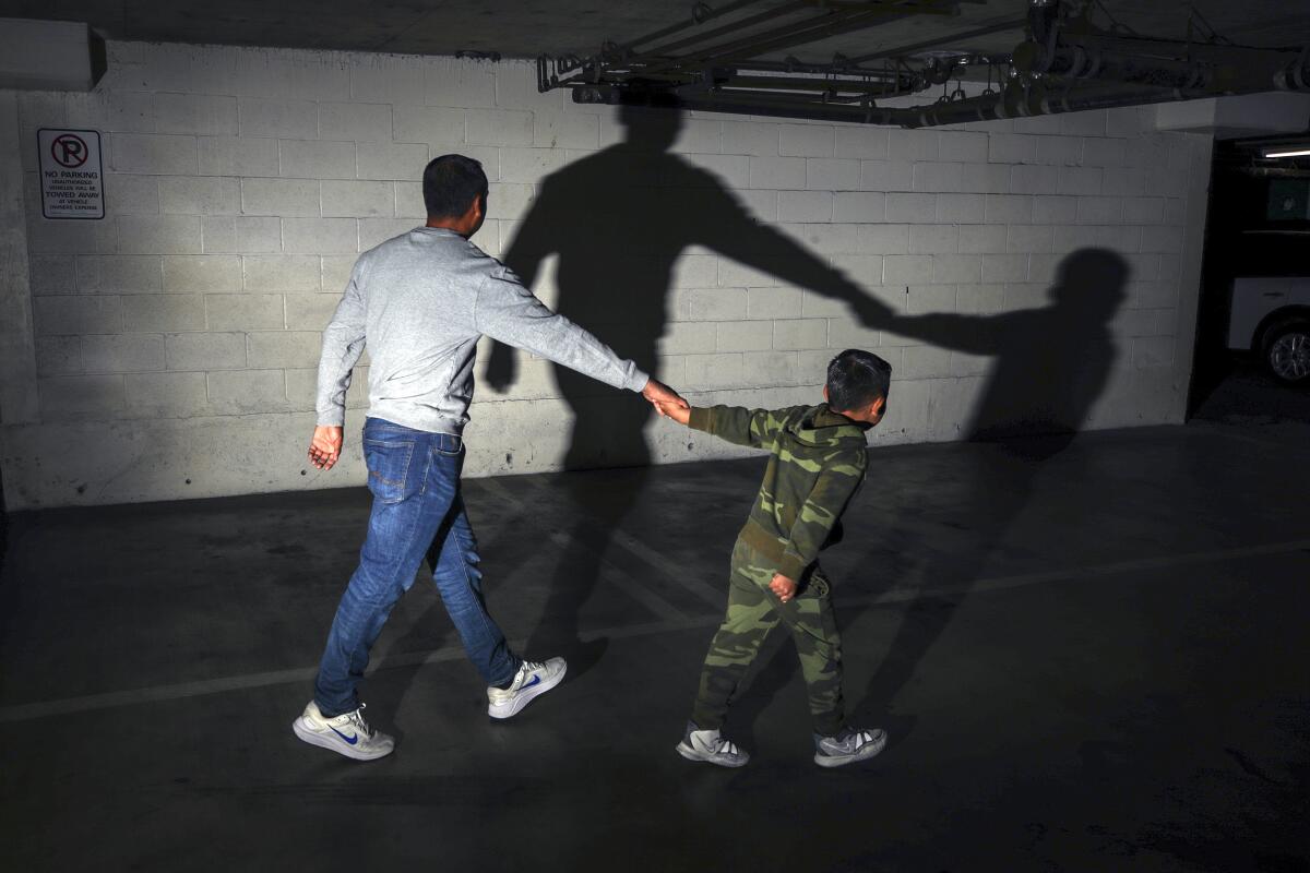A father holds his young son's hand as they walk