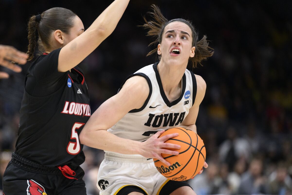 Iowa guard Caitlin Clark, right, looks for an open shot as Louisville guard Mykasa Robinson (5) defends in the first quarter of a Sweet 16 college basketball game of the NCAA Tournament in Seattle, Sunday, March 26, 2023. (AP Photo/Caean Couto)