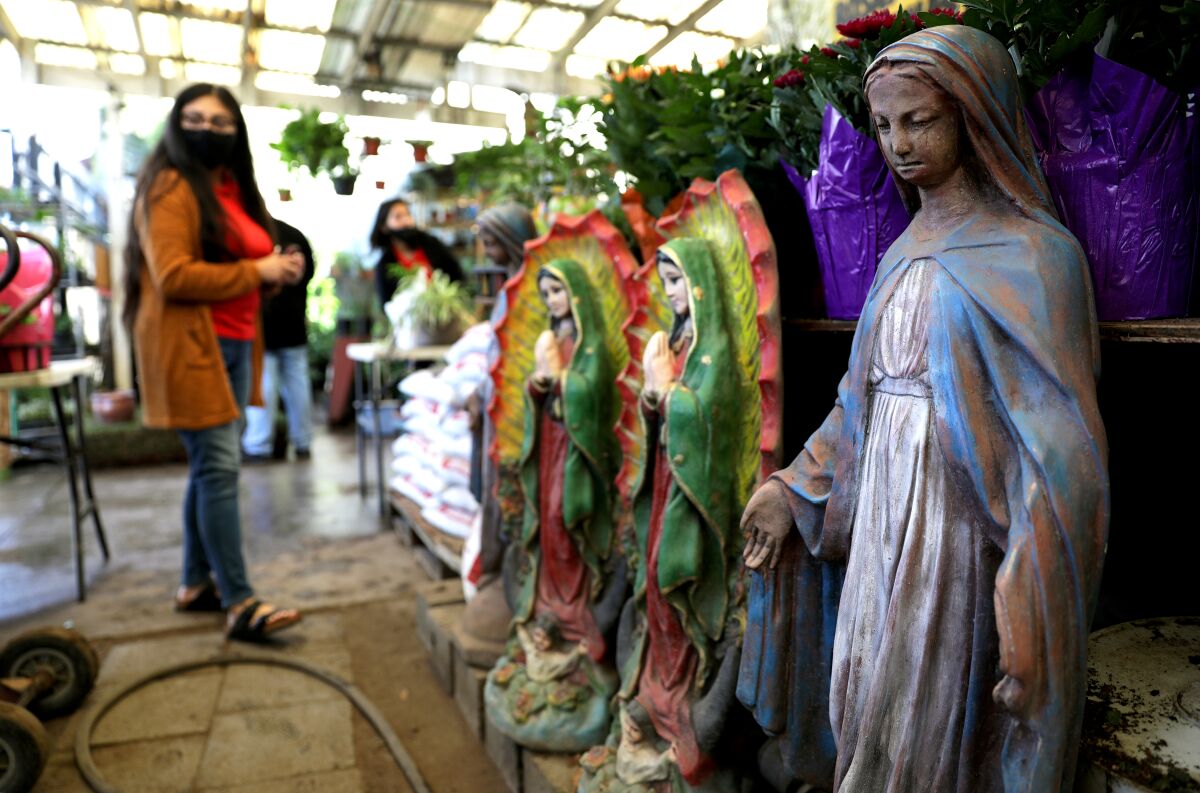 A woman browses near Our Lady of Guadalupe statues at Avalon Nursery & Ceramics in South Los Angeles.