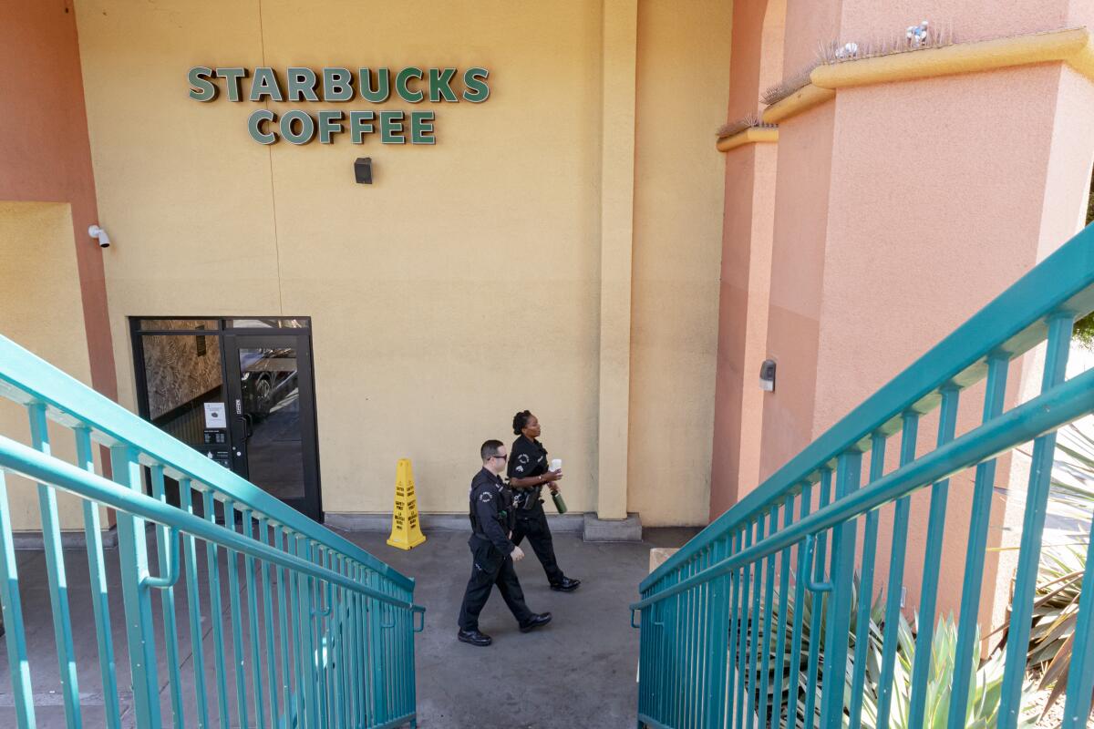 Two police officers walk behind a Starbucks 