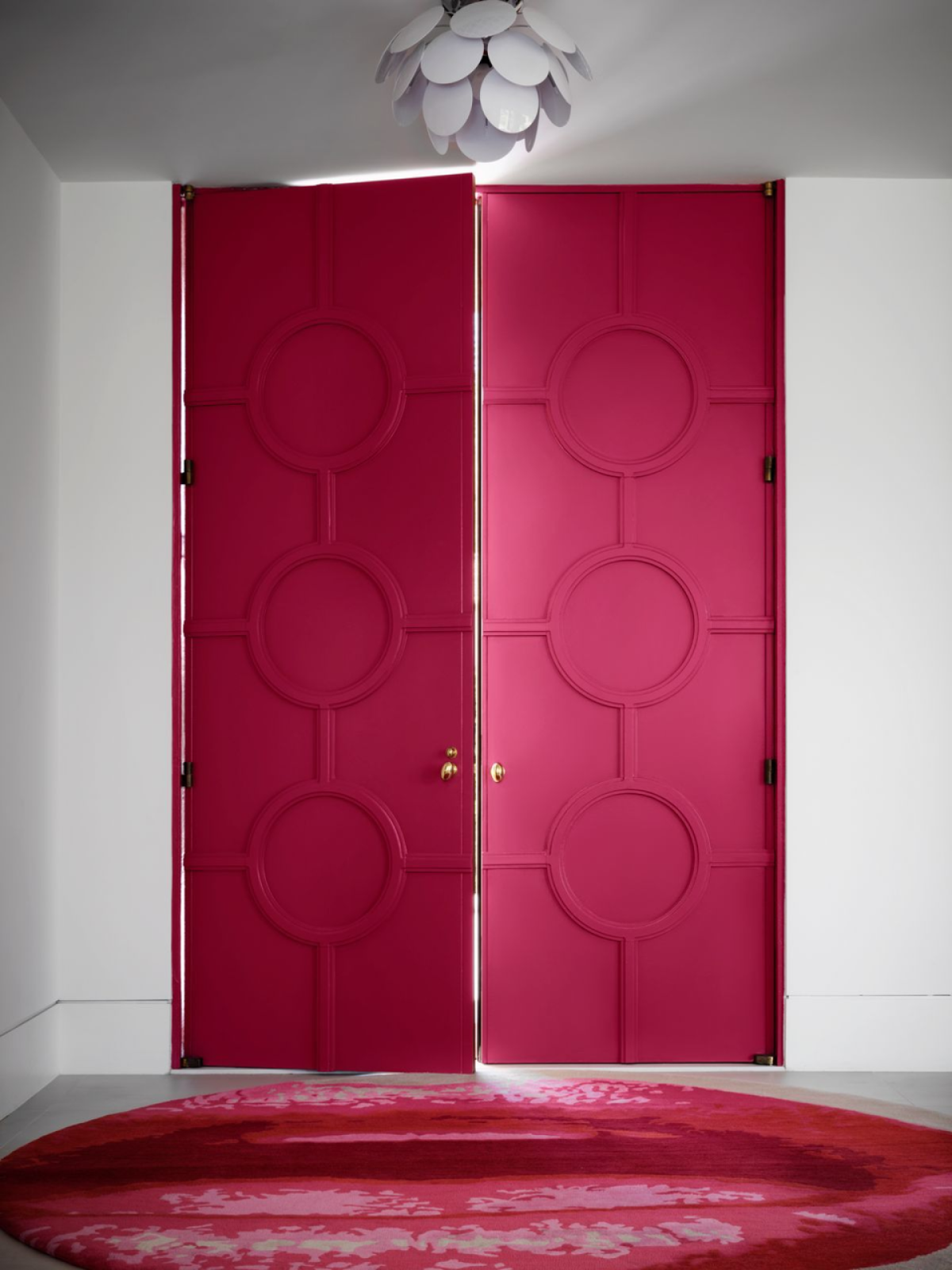 An entry door is a deep red color on the interior, with a funky rug that looks like lips.