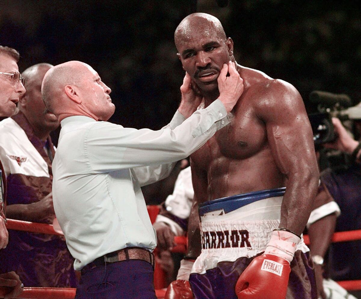 Evander Holyfield is checked by referee Mills Lane after he was bit on the right ear by Mike Tyson.