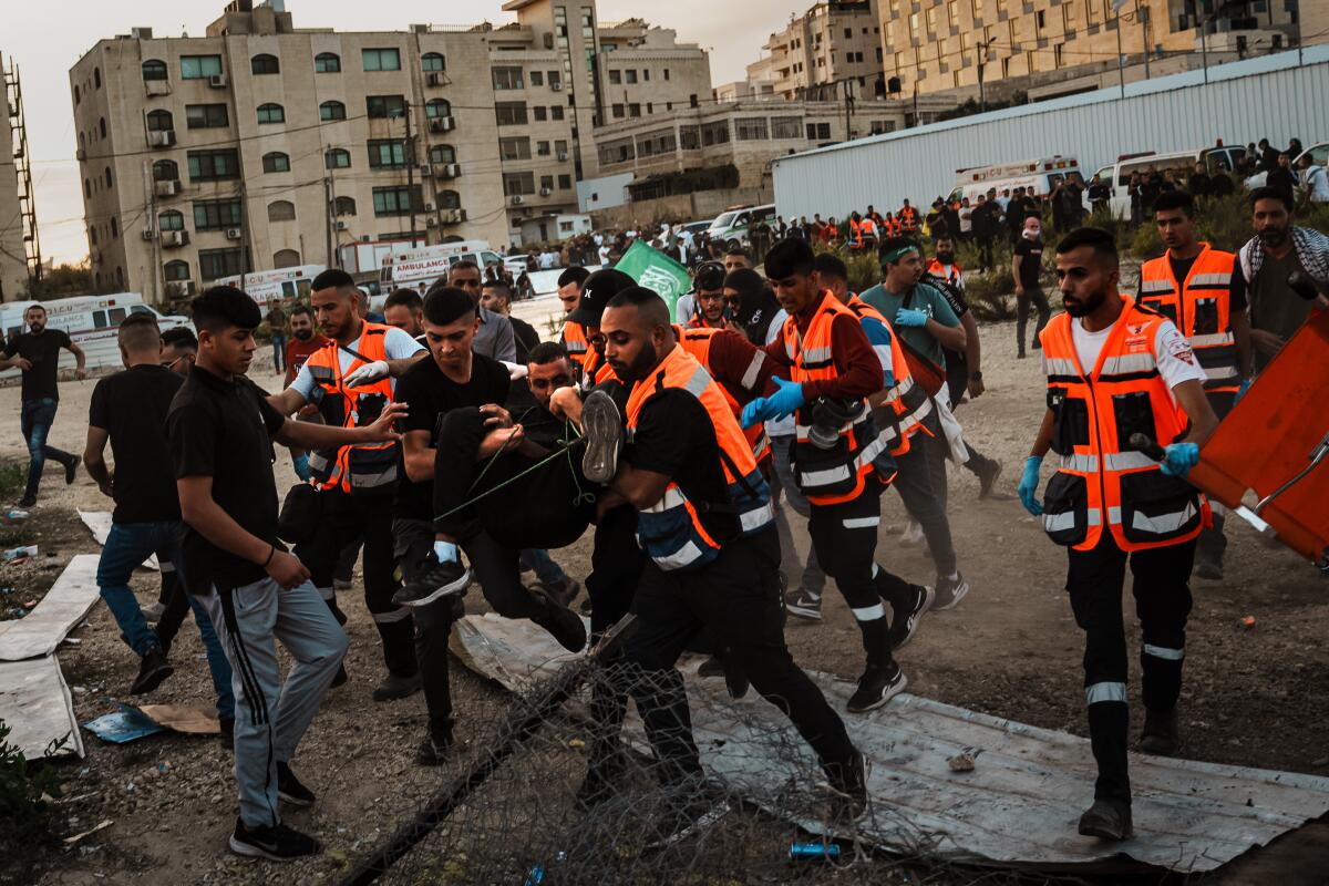 Paramedics carry a wounded Palestinian protester toward the ambulance after he was shot by Israeli forces.
