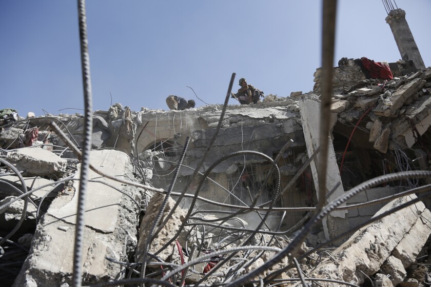 Personas retiran escombros de una instalación penitenciaria que fue objeto de un ataque aéreo de la coalición que encabeza Arabia Saudí y en el que murieron al menos 87 personas en un bastión de rebeldes hutíes en la frontera con Arabia Saudí, el sábado 22 de enero de 2022, en la provincia norteña de Sa'dah, Yemen. (AP Foto/Hani Mohammed)